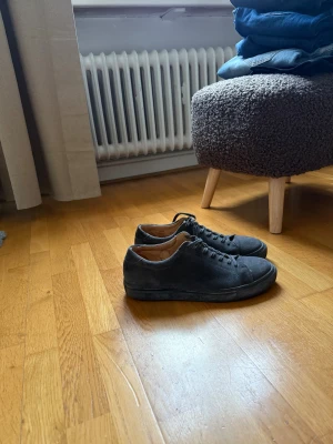 Svarta mockasneakers från Myrqvist 43 - Stilrena svarta sneakers från Myrqvist i mjuk mocka med rund tå och platt sula. Skorna har klassisk snörning och en minimalistisk design som passar till det mesta. Insidan är fodrad i ljust skinn för extra komfort.