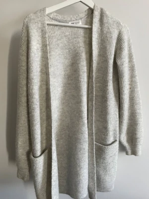 Ljusgrå ribbad kofta från H&M - Mysig ljusgrå kofta från H&M i storlek 164 (barnavdelningen). Den är ribbstickad, har långa ärmar och två stora fickor. Enkel och stilren design. 