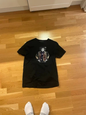 Svart t-shirt med tryck från Limitato - Svart t-shirt från Limitato med coolt grafiskt tryck på bröstet. Klassisk passform med rund hals och korta ärmar. Materialet känns mjukt och skönt, perfekt till jeans eller shorts. Snygg och stilren design som sticker ut.