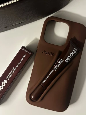 Rhode mobil skal iPhone 15 - Läppglanset är helt nytt och har ej används eller testat. Mobilskalet är till IPhone 15. I färgen Espresso