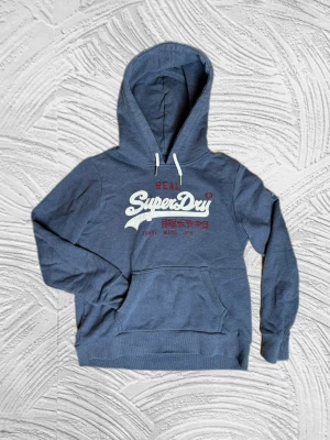 Superdry Hoodie - Fet superdry hoodie, passar S/M– enkel att matcha och skön att bära. Ett stilrent val, noggrant utvalt med omsorg av A.M.C!  📩 Frågor? Hör gärna av dig! 📲 Följ oss här på Plick för fler uppdateringar. ♻️ Tack för att du handlar mer hållbart med A.M.C Archive!