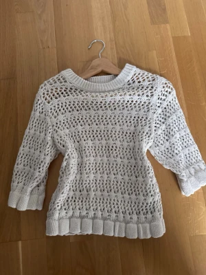 Vit stickad tröja från Amisu - Säljer en vit stickad tröja från Amisu i storlek S. Tröjan har ett snyggt hålmönster och ribbade muddar vid ärmslut och nederkant. Perfekt för lager-på-lager och passar till både jeans och kjol. Rund hals och trekvartsärm ger en chill vibe.