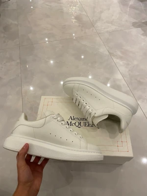 Vita sneakers från Alexander McQueen (storlek 43-44) - Fick skorna i födelsedagspresent men jag valde att sälja dem eftersom det inte passa min storlek. Ett par vita sneakers från Alexander McQueen.Skorna har snörning och är tillverkade i slätt skinn. Perfekta för dig som gillar minimalistisk design och vill ha ett par lyxiga sneakers i garderoben.