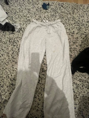 Grå mjukisbyxor från H&M Divided - Säljer ett par ljusgrå mjukisbyxor från H&M Divided i storlek S. Byxorna har elastisk midja med snörning och är tillverkade i mjuk bomull. Perfekta för chill dagar hemma eller när du vill vara extra bekväm. Klassisk basic-stil med loose passform.