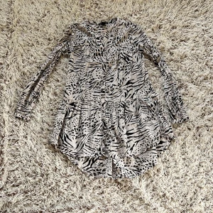 Beige/rosa och svart leopard blus från H&M - Lång blus från H&M i beige med svart leopard- och zebramönster. Modellen har långa ärmar, knappar framtill och lätt rynkad kjol. Tillverkad i tunn bomull, perfekt för dig som gillar djurmönstrat och vill sticka ut. Den är inte stretchig. Material är väldigt lätt och luftigt. Storlek EUR 36