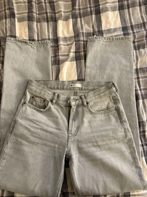 Grå jeans från Gina tricot - Säljer ett par grå jeans med raka ben. Jeansen har en ljusgrå tvätt. Passar dig som vill ha ett par jeans med normal passform och låg midja.