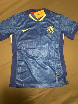 Chelsea FC tröja  - Chelsea FC matchtröja i blått med Palmer och nummer 10 på ryggen. Tröjan har klubbmärke på bröstet . Perfekt för fotbollsfans.