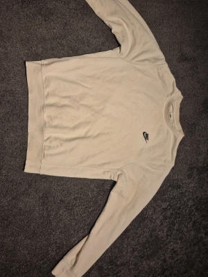 Vit Tjocktröja - Nike - Säljer en stilren vit långärmad tröja från Nike med broderad logga på bröstet. Tröjan har rund hals, ribbade muddar och är gjord i mjuk bomull. Grym passform, grym kvalitet, hållbart och mjukt bomull.