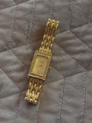 Guld klocka  - Bilderna visar en guldfärgad klocka med rektangulär urtavla och glittriga detaljer super fin och kan ändra storleken 🥰säljer för att jag aldrig använder klockor köpt på SHEIN men väldigt bra skick för att va från SHEIN 🥰