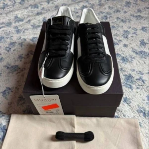 Valentino Flycrew - Säljer ett par snygga Valentino Garavani flycrews i svart och vitt skinn med klassisk rund tå och platt sula. Skorna har svarta snören och en vit kontrastpanel på sidan. Märkeslogga på plösen och innersulan. Kommer med originalkartong, dustbags och extra skosnören.