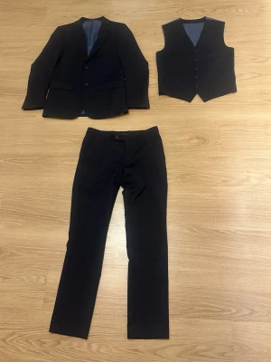 Mörkblå kostym från Dressmann, slim fit - Dressman kostym i storlek 46 (med kommer 1 kavaj, 1 väst och 1 par kostym byxor) skulle säga att den är i mycket bra skick då man inte kan se slitage någon stans. Hör av er vid frågor eller funderingar (vit skjorta kan skickas med de e bara att skriva om ni skulle vilja de)