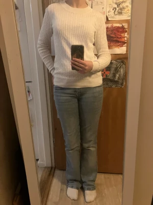 Vit kabelstickad tröja Gina Tricot - Säljer en vit kabelstickad tröja från Gina Tricot i storlek S. Tröjan har rund hals, långärmade ärmar och ribbade muddar vid hals, ärmslut och nederkant. Materialet är mjukt och stickat, perfekt för kyliga dagar. Snygg och enkel att matcha med jeans eller kjol. Har även ett lagat hål vid armhålan, det syns knappt. 