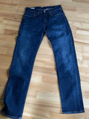 Levi's 502 jeans straight fit - Säljer ett par klassiska Levi's 502 jeans i mörkblå som är i mycket bra skick. Jeansen passar till allt och ger en avslappnad look (nypris 1200kr) Passformen är straight fit. W31 L34. Hör av er vid funderingar!