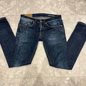 dondup george - lappen är av men storlek 29 passar 30 Snygga blå jeans från Dondup, modell George, med coola slitningar och kontrastsömmar. Klassisk femficksdesign och raka ben. Tillverkade i Italien med en tvättad look och tobaksfärgade sömmar som ger extra edge. Perfekt för dig som gillar en avslappnad stil.