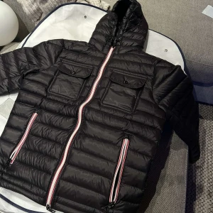 Svart Moncler pufferjacka med huva - Svart pufferjacka från Moncler med huva och snörning. Jackan har två bröstfickor med knapp, två sidofickor med dragkedja i rött, vitt och blått. Moncler, endast seriösa köpare,