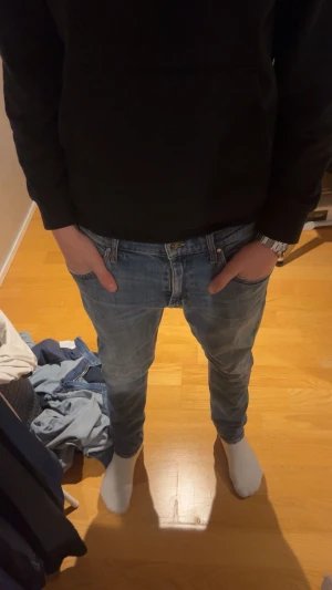 Blå jeans från Tiger of Sweden - Snygga blå jeans från Tiger of Sweden med klassisk femficksdesign och bruna detaljer vid linningen. Jeansen har raka ben och en stilren look som passar till det mesta. Perfekta för dig som gillar tidlös stil.