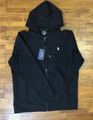 Svart hoodie från Polo Ralph Lauren  - Svart hoodie från Polo Ralph Lauren med klassisk huva och dragkedja framtill. Tröjan har långa ärmar, två fickor och den ikoniska vita Polo-loggan broderad på bröstet. Perfekt för en chill och stilren look.