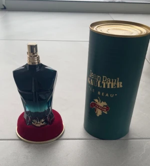 Jean Paul Gaultier-le beau le parfum - Säljer denna ikoniska och sensuella herrdoft från Jean Paul Gaultier. Flaskan kommer i den klassiska skulpturformade designen, riktigt snygg som prydnad också!Denna parfym är Fräsch, varm och förförisk. Toner av kokos, tonkaböna, ambra och träiga inslag som gör den både djup och frisk på samma gång. Denna är 75 ml med cirka 90-95% kvar i flaskan!Ny pris på denna är 800-1100kr(för en äkta) och denna är såklart äkta!