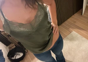 Olivgrön linnetopp med spetsdetaljer - Säljer en olivgrön linnetopp med v-ringad hals och bred spetskant både upptill och nedtill. Toppen är ärmlös och har en mjuk, glansig yta som ger en lyxig känsla. Perfekt för dig som gillar stilrena och feminina detaljer.💕