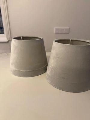 2 grå lampskärmar i sammet - Jag säljer 2 eleganta grå lampskärmar i sammetstyg, passar både bordslampor och golvlampor. Fäste för E14-sockel. Ger ett mjukt och stilrent intryck till hemmet.