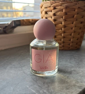 Rebecca Stella GIA parfym - Snygg parfym med rosa detaljer från Rebecca Stella. Perfekt för dig som vill ha en trendig accessoar på sminkbordet. Flaskan har en modern look som passar unga och stilmedvetna. 50 ml, litegrann använts 