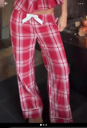 Pyjamasbyxor Gina tricot  - Säljer ett par röda mjukisbyxor med vitt rutmönster och en stor vit rosett framtill i midjan. Byxorna har en loose passform och är tillverkade i mjukt bomullsmaterial, perfekta för att chilla hemma. Helt nya säljer då jag köpt fel storlek endast testade. Kom med prisförslag. Köpta från Gina tricot Young kollektionen 