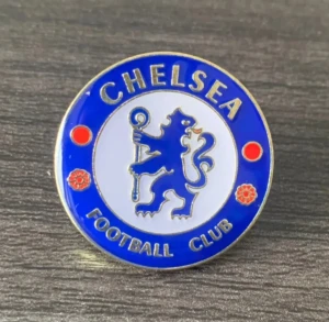 Chelsea FC blå och vit pin - Snygg rund pin med Chelsea FC:s klassiska lejonlogga i blått och vitt, med guldfärgade detaljer och text. Perfekt för att visa ditt stöd för laget på jackan eller väskan. Ikonisk design med röda och blå inslag.