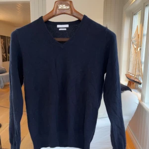 Mörkblå kashmirtröja från MONO - Mjuk och lyxig mörkblå tröja från MONO i ren kashmir. Tröjan har v-ringad hals och långa ärmar, perfekt för dig som gillar stilrena och klassiska plagg. Passformen är normal och materialet känns riktigt skönt mot huden.