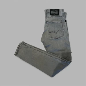 Replay Anbass slim jeans! - Snygga grå Replay Anbass jeans i slim fit med klassisk femficksdesign och svarta sömmar. Jeansen har raka ben och en stilren look. Skicket på jeansen är enligt mig riktigt bra! Storleken är W31 L32. Dem har blivit lagade över skrevet vid rumpan lite, nästan osynligt! Vid fler frågor är det bara att höra av er!