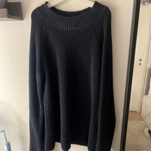Mörkblå stickad tröja med bred krage - Säljer en mörkblå stickad tröja med bred ribbad krage och långa ärmar. Tröjan har en loose passform och är perfekt för kyliga dagar. Materialet är grovstickat och ger en skön och avslappnad vibe. Passar dig som gillar enkel och stilren design.
