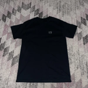 Svart Hov1 t-shirt vi dansar vidare i livet - Svart t-shirt från Hov1 i storlek M med klassisk kronlogga på bröstet och stort turnétryck på ryggen med texten 'Vi Dansar Vidare I Livet' och turnédatum. Skön passform och mjukt material, perfekt för dig som gillar svensk musik.