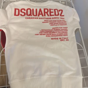 Vit och röd sweatshirt från DSQUARED2 - Säljer en vit sweatshirt från DSQUARED2 med stor röd lönnlöv-tryck på framsidan och röd text på ryggen. Tröjan har ribbade muddar och rund hals. Materialet är mjuk bomull och passformen är normal. Perfekt statement-plagg för dig som gillar snygga prints.