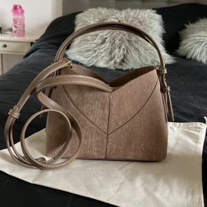 Beige väska från Zara - Stilren beige axelväska med cool geometrisk form och snygga sömmar. Väskan har både handtag och axelband. Aldrig använd så prislappen är kvar. Man kan även böja sidorna inåt som man ser på bild 3. Pris går att diskutera!😇💕