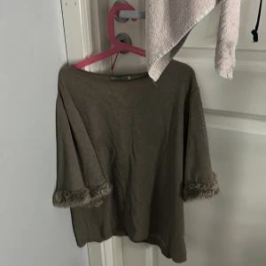 Beige topp med fuskpäls från Zara - Säljer en topp från Zara Collection med trekvartsärmar och fuskpälsdetaljer vid ärmsluten. Toppen har en loose passform och är perfekt för dig som gillar unika detaljer. Tillverkad i mjukt material och passar snyggt till både jeans och kjol.