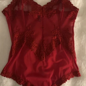 Röd spetsbody från Intimissimi - Använd en gång! Säljer en snygg röd body från Intimissimi i storlek S. Den har transparent mesh och vackra spetsdetaljer framtill och längs kanterna. Modellen är ärmlös och har en v-ringad form som ger en feminin look. Perfekt för dig som vill ha något extra till din outfit. Org pris 560kr