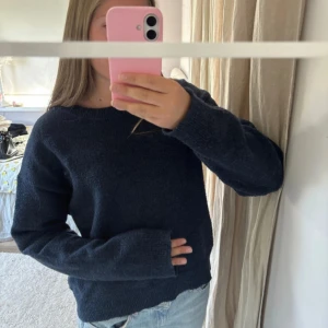 Mörkblå stickad tröja - Mysig mörkblå stickad tröja med rund halsringning och långa ärmar. Perfekt för kyligare dagar och enkel att matcha med jeans eller kjol. Tröjan har en klassisk passform och är riktigt skön att bära.