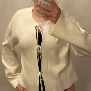 Vit kofta med snörning fram från Gina tricot  - Säljer en vit kofta med snygg snörning framtill i tre knyt. Koftan har långärmade ärmar och är super mjuk. Använd fåtal gånger☺️