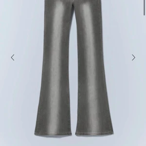 Grå bootcut jeans med slitningar - Säljer ett par grå bootcut jeans med slitna detaljer vid knäna och råa kanter nertill. Jeansen har en snygg tvättad look och breda ben som ger en retro vibe. Perfekta för dig som gillar en avslappnad och trendig stil. Klippte hålen själv.