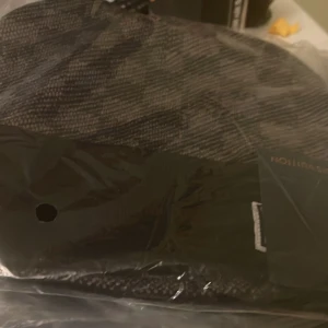 Mörkgrå stickad mössa - Säljer en snygg mörkgrå stickad mössa med diskret mönster. Perfekt för kalla dagar och passar till de flesta stilar. Mössan har en klassisk form och är tillverkad i mjukt stickat material som håller dig varm.