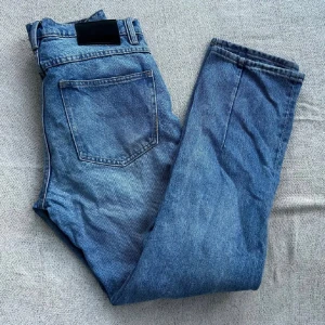 Blå jeans från Neuw Stockholm - Snygga blå jeans från Neuw Stockholm med klassisk femficksdesign och knappgylf. Jeansen har en rak passform och är tillverkade i slitstarkt denimtyg