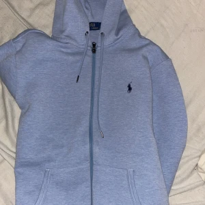 Ljusblå hoodie från Polo Ralph Lauren - Ljusblå hoodie från Polo Ralph Lauren 9.5/10 skick! Nästan helt oanvänd, använd ca 5 gånger. Säljes för den blivit för liten för mig och kommer ej till användning, köptes för runt 2200kr säljes för 1150kr kan gå ner i pris vid snabb affär! Hör av er vid intresse! Gör inga byten! Passar dig som är runt 170 