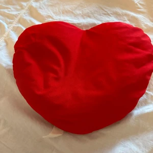 Hjärtkudde röd - Stor röd hjärtkudde, ca 40 cm bred och 30 cm hög. Mjuk och bekväm, perfekt som dekoration eller present. Kudden är i gott skick, men etiketten är något sliten och har några lösa trådar. Inköpt från TGR