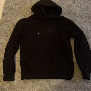 Svart hoodie från Lexington - Säljer en svart hoodie från Lexington i storlek S. Tröjan har huva med snörning och långa ärmar. Perfekt för dig som gillar en stilren och enkel look. Har aldrig använt den så helt nytt skick. Tröjan är hyfsat stor i storleken. Passar bäst om du normalt sätt har M i tröjor. Pris kan diskuteras vid snabb affär. 