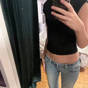 Svart croppad topp med öppen rygg - Säljer en svart croppad topp med öppen rygg och ärmlös design. Toppen har en tight passform och är tillverkad i mjukt stretchigt material, perfekt för dig som gillar minimalistisk stil och vill visa lite hud. Enkel och snygg att matcha med jeans eller kjol.