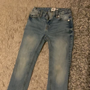 Slim fit ljusblå jeans från 157 - Snygga ljusblå jeans från 157 i slim fit-modell. Jeansen har klassisk femficksdesign, bälteshällor och dragkedja. De är tillverkade i stretchigt denim för en bekväm passform och har slitningar framtill för en cool look.