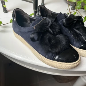 Svarta sneakers med päls och rosett - Unika svarta sneakers med pälsdetaljer och breda satinrosetter. 