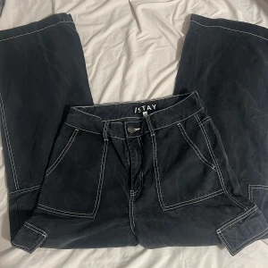 Svarta cargopants från IStay - Svarta cargopants från carlings med kontrasterande vita sömmar. Byxorna har flera stora fickor på sidorna och bak, samt breda ben och hög midja. Tillverkade i ett slitstarkt bomullstyg, perfekta för en avslappnad streetstil. Köpta för 599kr
