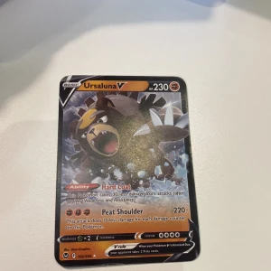 Ursaluna V - Cool Pokémon-kort med Ursaluna V! Perfekt för dig som samlar eller spelar Pokémon TCG. Kortet har 230 HP och kraftfulla attacker som Hard Coat och Peat Shoulder. Snygg design och passar både nybörjare och erfarna spelare. Gör din samling ännu vassare!