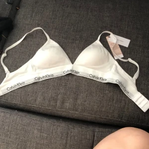 Vit topp från Calvin Klein - Snygg vit triangeltopp från Calvin Klein med justerbara axelband. Helt ny endast testad och den va för liten för mig (har 75B). Lappen är bort dragen men har kvar den som ni ser på bilden. orginalpriset va 460 ca så tänker inte gå ner i pris eftersom den är helt ny 💕