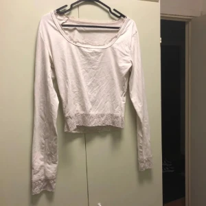 Vit långärmad topp med spetsdetaljer - Söt vit långärmad topp med bred, rundad urringning och gulliga spetsdetaljer vid halsringning, ärmslut och nederkant. Den är lite stretchig väldigt mjuk bomull (men tunn) den är S men passar M oxå